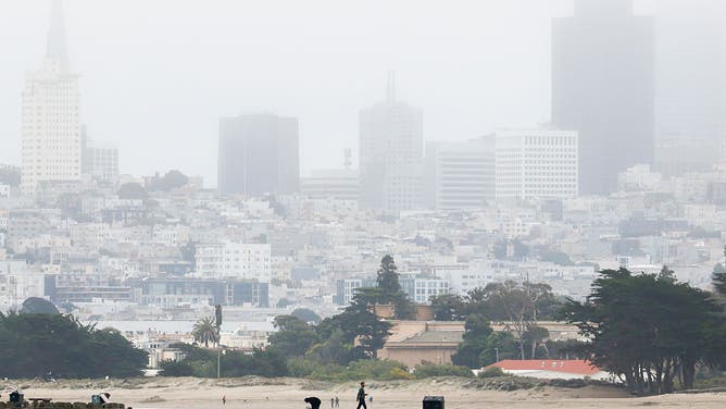 A person walks along Torpedo Wharf near Crissy Field as fog shrouds the downtown view of San Francisco, California Wednesday, July 16, 2025. 