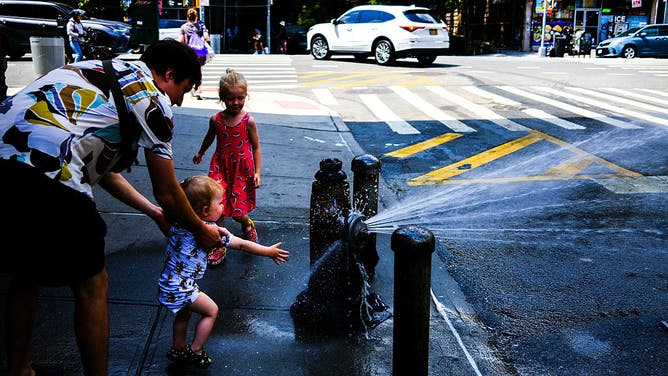 A family cools off with fire hydrant water in the Hamilton Heights neighborhood in the Manhattan borough of New York City, as the region is under an extreme heat warning on July 25, 2025.