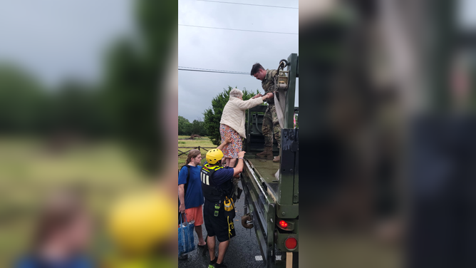 Betty Matteson climbing into the back of a truck following the flooding.