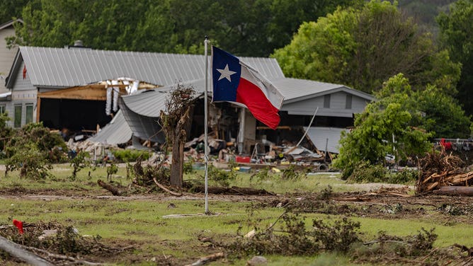 A Texas state flag flies in a yard filled with debris on July 6, 2025 in Hunt, Texas.
