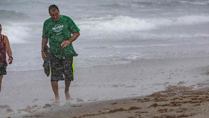 FILE - A couple walks through the rain on Cocoa Beach on September 28, 2022. (Photo by Jim WATSON / AFP) (Photo by JIM WATSON/AFP via Getty Images)