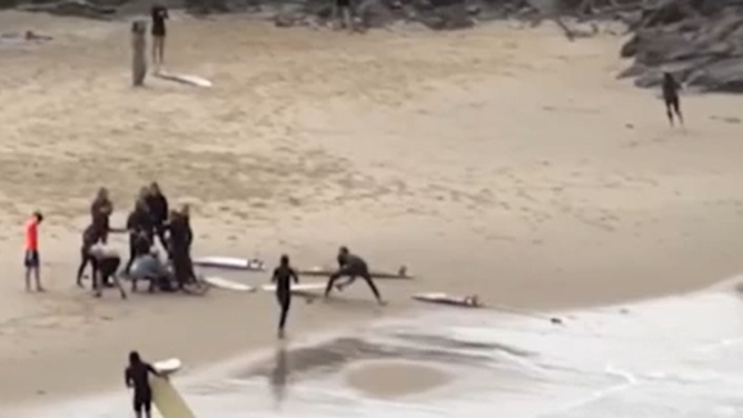 People come to the injured surfer's aid on the beach.