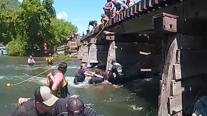 The officers work to get the woman to shore after freeing her.