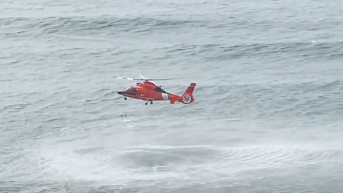The rescue swimmer swims over to the lifeguards and the girl.