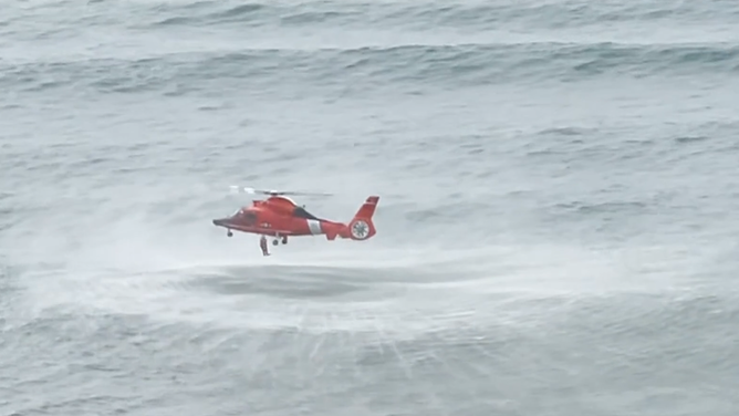 The rescue swimmer drops from the helicopter to save the girl.