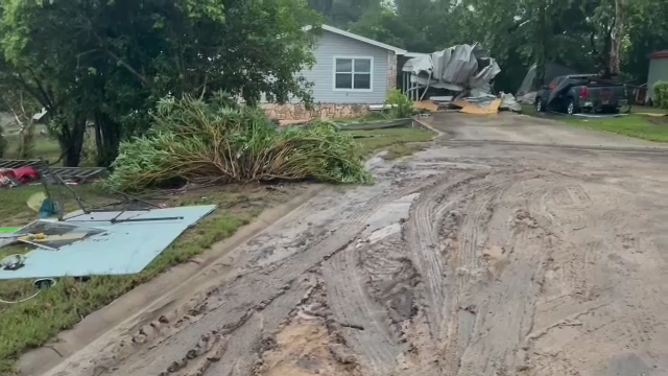 Sediment and debris lie in driveway after the Fourth of July flood in Kerrville, TX. Note the crumpled up carport in the background.