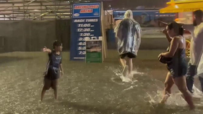 This image shows people wading through floodwaters at the Wisconsin State Fair in West Allis on Saturday, Aug. 9, 2025.