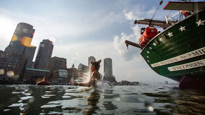 Costumed revelers walk the plank and jump off the tall ship Denis Sullivan and into Boston Harbor during a heatwave in Boston, Massachusetts, on June 20, 2024.