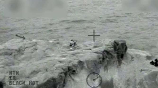 A wide shot of the children huddled on the rock.