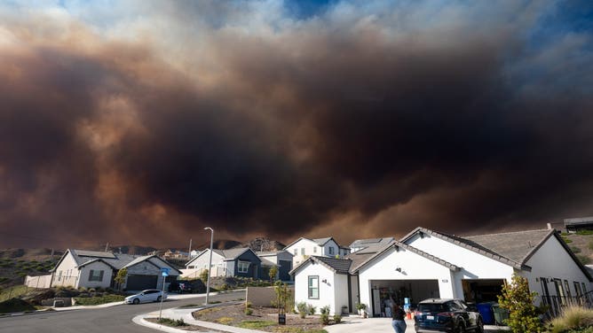 Smoke from the Canyon Fire rises above homes along Old Springs Road in Val Verde on Monday, August 7, 2025.