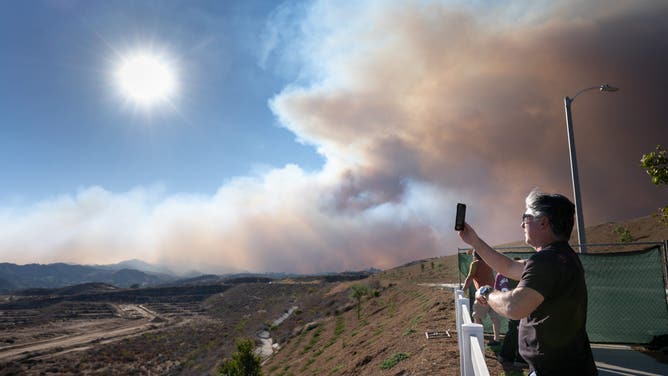 A resident takes photos of the Canyon Fire as it pushes towards Castaic on Monday, August 7, 2025.
