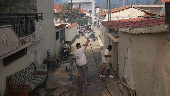 Locals are carrying out a cooling operation against the forest fire with hoses as firefighters continue their efforts to extinguish the fire that broke out in the forest area near the Komotini, Greece on August 10, 2025
