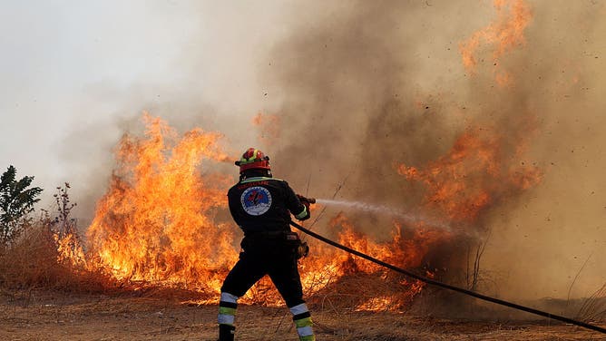 Flames and smoke rise from burning trees while firefighters continue their efforts to extinguish the fire that broke out in the forest area near the Komotini, Greece on August 10, 2025.
