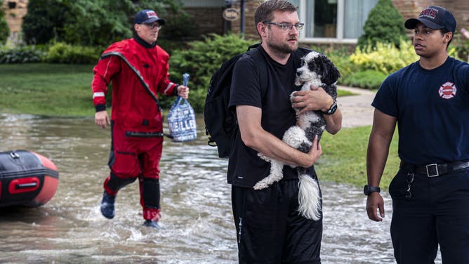 WAUWATOSA, WISCONSIN - AUGUST 10: First responders rescue people from flooding in their homes on August 10, 2025 in Wauwatosa, Wisconsin. Heavy downpours brought as much as 13 inches of rain to parts of southeast Wisconsin overnight, resulting in widespread flooding across the region. (Photo by Andy Manis/Getty Images)