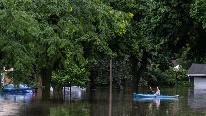 WAUWATOSA, WISCONSIN - AUGUST 10: A kayaker navigates flooding on August 10, 2025 in Wauwatosa, Wisconsin. Heavy downpours brought as much as 13 inches of rain to parts of southeast Wisconsin overnight, resulting in widespread flooding across the region. (Photo by Andy Manis/Getty Images)