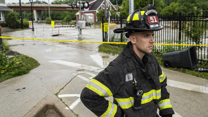 WAUWATOSA, WISCONSIN - AUGUST 10: A firefighter watches over flooding on August 10, 2025 in downtown Wauwatosa, Wisconsin. Heavy downpours brought as much as 13 inches of rain to parts of southeast Wisconsin overnight causing floods across the region. (Photo by Andy Manis/Getty Images)