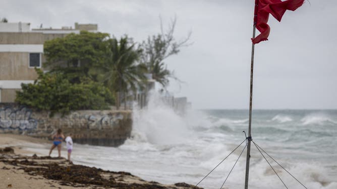 A ripped red flag warning of rip current waves as Category 5 Hurricane Erin approaches in San Juan, Puerto Rico, on August 16, 2025. Hurricane Erin on Saturday strengthened to a "catastrophic" Category 5 storm as it barrelled towards the Caribbean, with weather officials warning of possible flash floods and landslides. (Photo by Ricardo ARDUENGO / AFP) (Photo by RICARDO ARDUENGO/AFP via Getty Images)