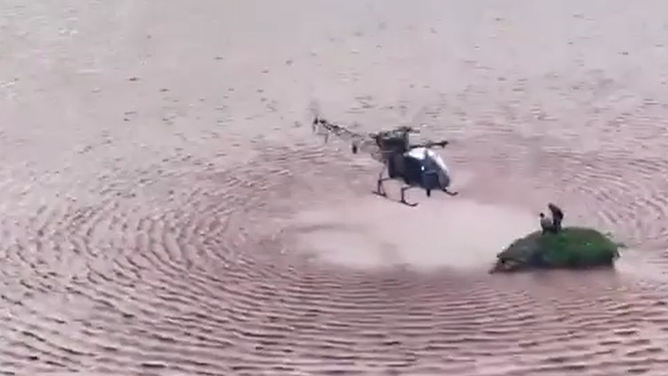 The helicopter approaches the small island to save the 2 people.