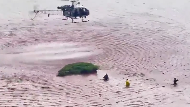 As the helicopter flies away, 3 people remain waiting rescue.