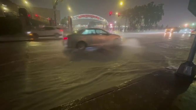 This image from FOX 6 News Milwaukee shows vehicles driving through floodwaters outside the Wisconsin State Fair in West Allis on Saturday, Aug. 9, 2025.