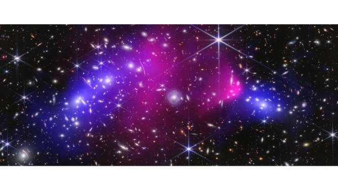 This is the central region of the Bullet Cluster, which is made up of two massive galaxy clusters. The vast number of galaxies and foreground stars in the image were captured by NASA’s James Webb Space Telescope in near-infrared light. Glowing, hot X-rays captured by NASA’s Chandra X-ray Observatory appear in pink. The blue represents the dark matter, which was precisely mapped by researchers with Webb’s detailed imaging.