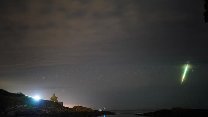 A fisherman watches a meteor during the Draconid meteor shower over Howick rocks in Northumberland. Picture date: Sunday October 10, 2021.