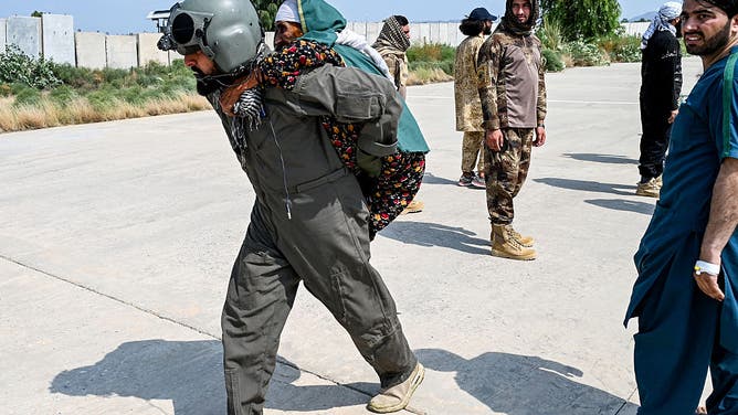 An Afghan military personnel carries an earthquake victim evacuated by a helicopter from the Nurgal district of Kunar province, after her arrival for medical assistance in Jalalabad on September 1, 2025. A massive rescue operation was underway in Afghanistan on September 1, after a strong earthquake and multiple aftershocks flattened homes in a remote, mountainous region, killing more than 800 people, the Taliban authorities said. (Photo by Wakil KOHSAR / AFP)
