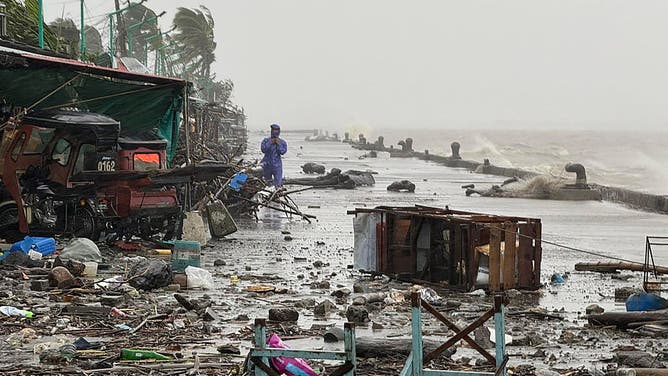 A man stands near debris on a waterfront road amid heavy rain due to weather patterns from Super Typhoon Ragasa in Aparri town, Cagayan province on September 22, 2025. Hundreds of families sheltered in schools and evacuation centres on September 22 as heavy rains and gale-force winds from Super Typhoon Ragasa lashed the northern Philippines and southern Taiwan.