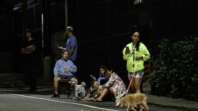 People sit outside their homes after an earthquake was felt in Caracas, Venezuela, on September 25, 2025. A 6.3-magnitude quake shook northwestern Venezuela late Wednesday, following a slightly smaller tremor in the area, the US Geological Survey reported. The most recent earthquake was felt in the capital Caracas, more than 600 kilometres away. (Photo by Juan BARRETO / AFP) (Photo by JUAN BARRETO/AFP via Getty Images)