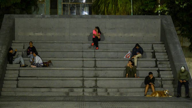People sit at a public square after an earthquake was felt in Caracas, Venezuela, on September 25, 2025. A 6.3-magnitude quake shook northwestern Venezuela late Wednesday, following a slightly smaller tremor in the area, the US Geological Survey reported. The most recent earthquake was felt in the capital Caracas, more than 600 kilometres away. (Photo by Juan BARRETO / AFP) (Photo by JUAN BARRETO/AFP via Getty Images)