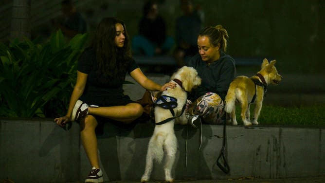 Two young women sit with their pets at a public square after an earthquake was felt in Caracas, Venezuela, on September 25, 2025. A 6.3-magnitude quake shook northwestern Venezuela late Wednesday, following a slightly smaller tremor in the area, the US Geological Survey reported. The most recent earthquake was felt in the capital Caracas, more than 600 kilometres away. (Photo by Juan BARRETO / AFP) (Photo by JUAN BARRETO/AFP via Getty Images)