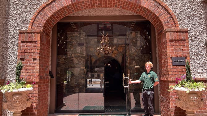 A worker holds open the door to the Grand Bohemian Lodge within Biltmore Village.