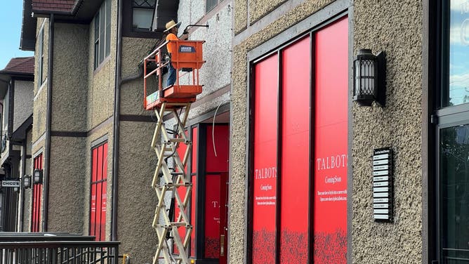 A worker installs a light outside a new talbot's store coming to Biltmore Village.