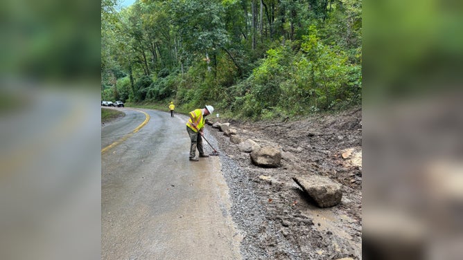 A worker pushes back gravel on the Gatlinburg Bypass after a landslide.