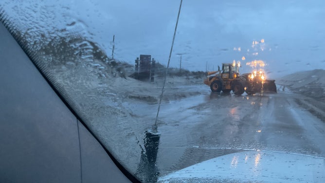 North Carolina Department of Transportation crews work to clear sand from Highway 12 on Hatteras Island, North Carolina on Saturday, Oct. 12, 2025.