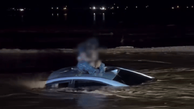 This image shows a man and child on the roof of a car stuck in floodwaters in Eloy, Arizona, before being rescued on Oct. 14, 2025.