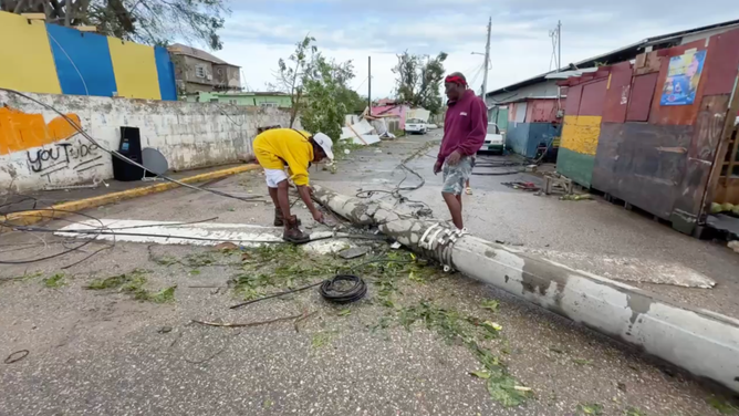 Men assess downed power pole.