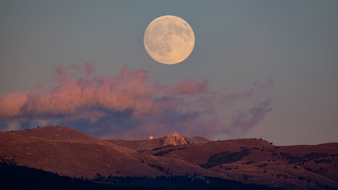 Harvest full moon rising above Rocca Calascio Castle and Santa Maria della Pietà church is seen from L'Aquila, Italy, on October 6th, 2025. October's full moon, also known as the "harvest moon", is the first 2025 supermoon, our satellite will appear about 14% bigger than usual. (Photo by Lorenzo Di Cola/NurPhoto via Getty Images)