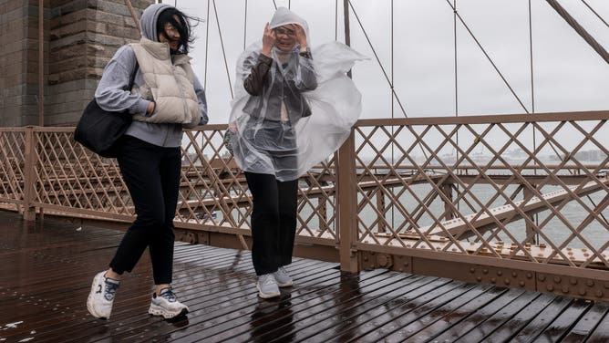 NEW YORK, NEW YORK - OCTOBER 13: People walk over the Brooklyn Bridge in the rain as New York City experiences wind and rain associated with a nor’easter storm moving through the region on October 13, 2025 in New York City. While New York City experienced only light rain and wind, thousands of residents in parts of New Jersey and Connecticut were without power. The storm caused New York City officials to cancel the annual Columbus Day Parade. (Photo by Spencer Platt/Getty Images)