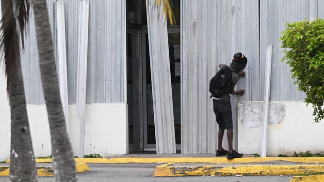 A man installs storm shutters at a business in preparation for the arrival of Hurricane Melissa in Portmore, St. Catherine parish, Jamaica, on October 25, 2025. Deadly storm Melissa strengthened Saturday afternoon into a Category 1 hurricane, with rapid intensification expected over the weekend as it cut a worryingly slow course toward the Caribbean island of Jamaica, forecasters said. (Photo by Ricardo Makyn / AFP) (Photo by RICARDO MAKYN/AFP via Getty Images)