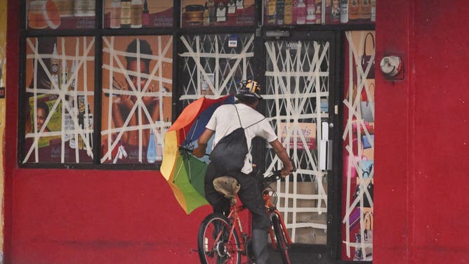 A cyclist rides up to a store to seek shelter from Hurricane Mellisa in Portmore on October 26, 2025. Hurricane Melissa was cutting a deadly path in the Caribbean on the night of October 25, with rapid intensification expected over the weekend as it took a worryingly slow course toward Jamaica and the island of Hispaniola, forecasters said. (Photo by Ricardo Makyn / AFP) (Photo by RICARDO MAKYN/AFP via Getty Images)