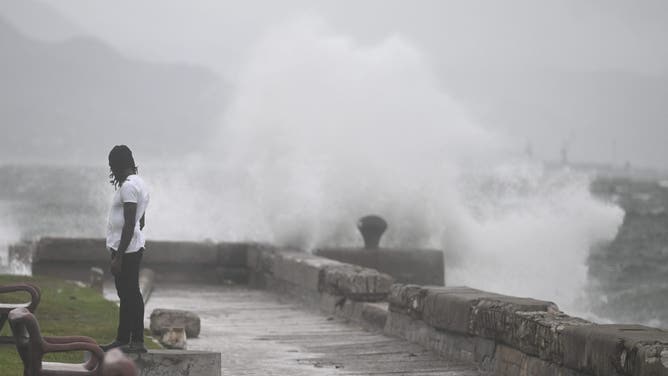 A man watches the waves crash into the walls at the Kingston Waterfront on October 27, 2025. Hurricane Melissa threatened Jamaica with potentially deadly rains after rapidly intensifying into a top-level Category 5 storm, as residents scrambled for shelter from what could be the island's most violent weather on record. Melissa has already been blamed for at least four deaths in Haiti and the Dominican Republic, and was set to unleash torrential rains on parts of Jamaica in a direct hit on the Caribbean island. (Photo by Ricardo Makyn / AFP) (Photo by RICARDO MAKYN/AFP via Getty Images)
