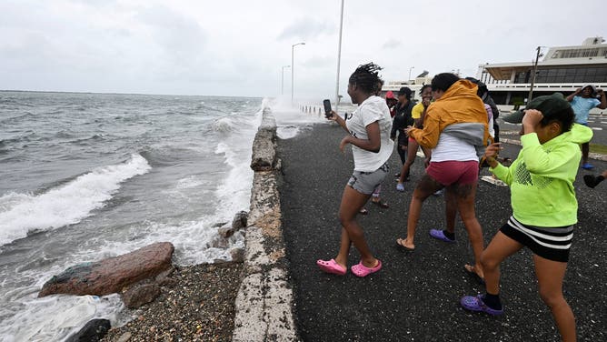 Teenagers gather at the Bank of Jamaica's car park on the Waterfront in Kingston on October 27, 2025. Hurricane Melissa threatened Jamaica with potentially deadly rains after rapidly intensifying into a top-level Category 5 storm, as residents scrambled for shelter from what could be the island's most violent weather on record. Melissa has already been blamed for at least four deaths in Haiti and the Dominican Republic, and was set to unleash torrential rains on parts of Jamaica in a direct hit on the Caribbean island. (Photo by Ricardo Makyn / AFP) (Photo by RICARDO MAKYN/AFP via Getty Images)