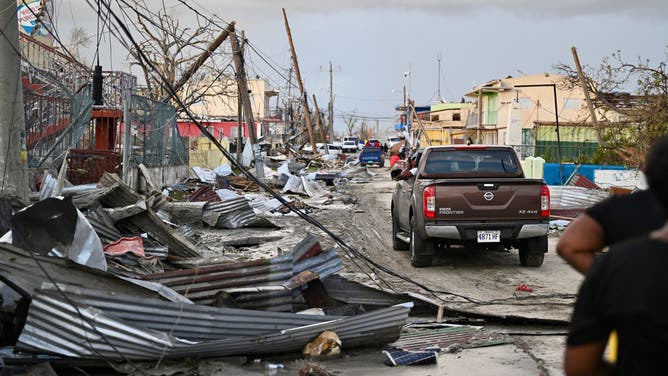 TOPSHOT - A car drives through the a destroyed neighborood following the passage of Hurricane Melissa, in Black River, Jamaica on October 29, 2025. Hurricane Melissa bore down on the Bahamas October 29 after cutting a path of destruction through the Caribbean, leaving 30 people dead or missing in Haiti and parts of Jamaica and Cuba in ruins.
