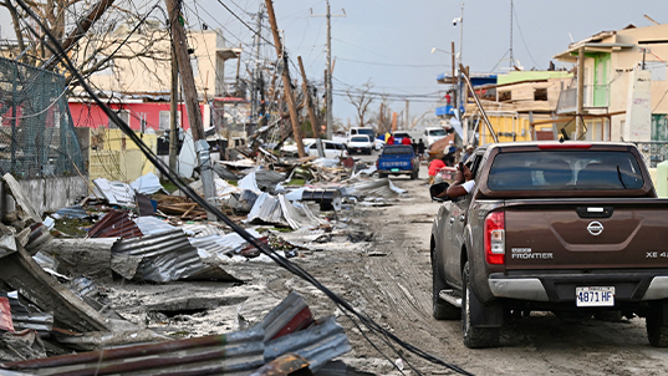 TOPSHOT - A car drives through the a destroyed neighborood following the passage of Hurricane Melissa, in Black River, Jamaica on October 29, 2025. Hurricane Melissa bore down on the Bahamas October 29 after cutting a path of destruction through the Caribbean, leaving 30 people dead or missing in Haiti and parts of Jamaica and Cuba in ruins.