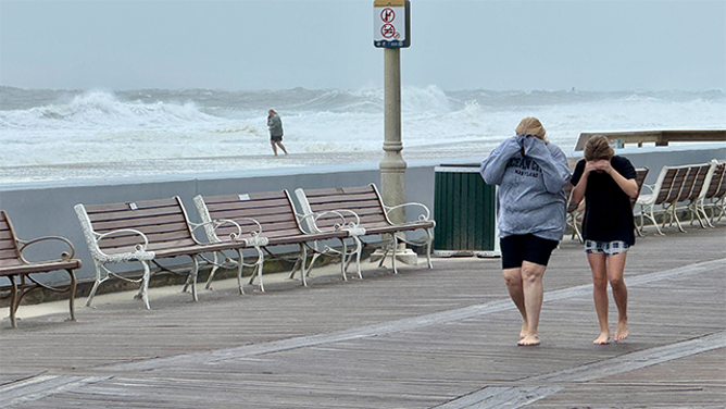 This photo shows people walking the boardwalk in Ocean City, Maryland, as a nor'easter batters the region on Oct. 12, 2025.