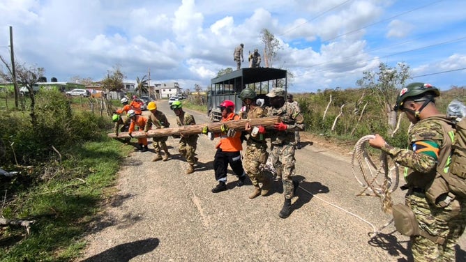 The Jamaica Defence Force and members of the El Salvador military work to remove a fallen power pole from a road in Jamaica on Monday, Nov. 10, 2025, after Hurricane Melissa.