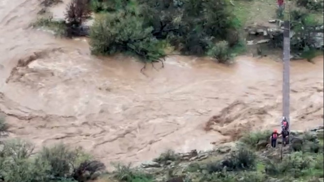 The rushing waters of Big Bug Creek as search and rescue teams stand at the banks of the creek.