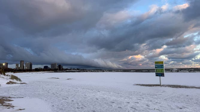 Another band of lake-effect snow looms in the distance over Lake Michigan in Chicago, after heavy bands of snow Sunday night.