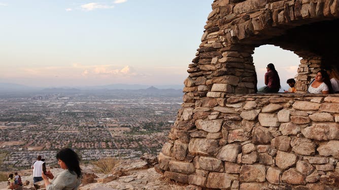 PHOENIX, ARIZONA - JULY 25: People gather and watch the sunset from South Mountain Park amid the city's worst heat wave on record on July 25, 2023 in Phoenix, Arizona. While Phoenix endures periods of extreme heat every year, today marked the 26th straight day of temperatures reaching 110 degrees or higher, a new record amid a long duration heat wave in the Southwest. Extreme heat kills more people than hurricanes, floods and tornadoes combined in an average year in the U.S.